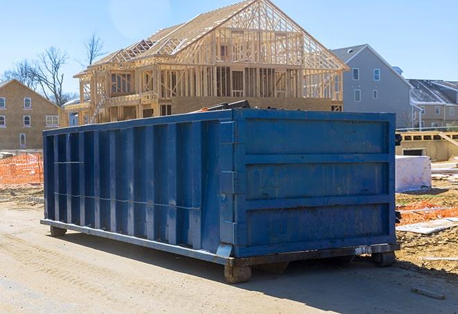 a green dumpster for recycling with stacks of cardboard boxes next to it